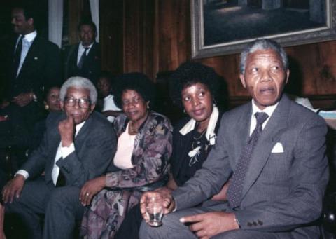 Albertina Sisulu and Winnie Mandela sit with their respective husbands