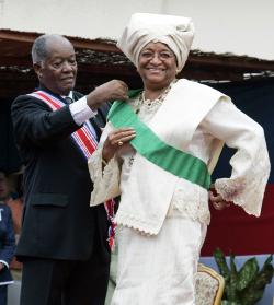 Ellen Johnson Sirleaf, dons the presidential sash with assistance from Liberia's Senior Ambassador-at-Large, George W. Wallace, Jr., during her inauguration ceremony at the Capitol Building in Monrovia, Liberia, January 16, 2006