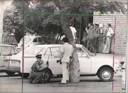 Police crouch behind cars while another group of officers negotiate with the trio