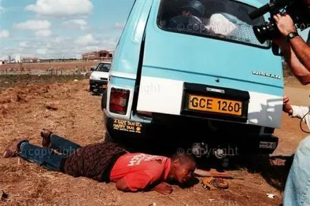 A cameraman films an ANC supporter hiding in the aftermath of the shooting
