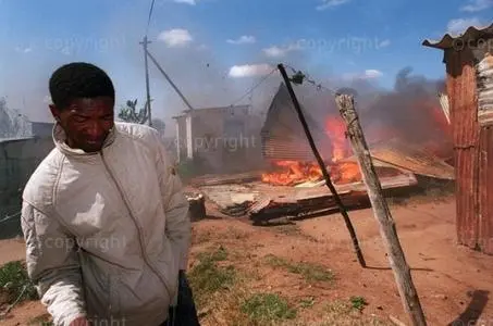 A man shies from a burning shack as pro ANC supporters in Ciskei homeland take revenge