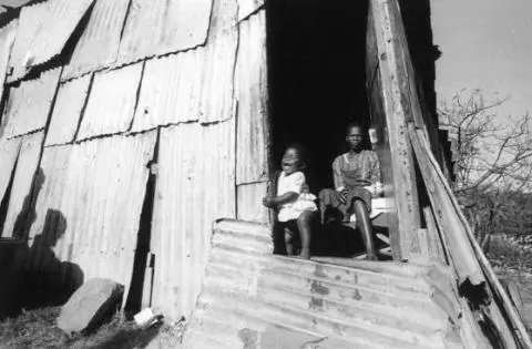 A mother and her child photographed in a corrugated iron shack