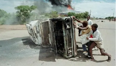 Residents overturn a burnt out car to form a barricade - Garankuwa, Boputhatswana March 1990