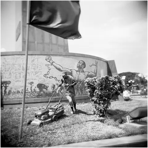 Man maintaining the lawn of the Monumento de Agostinho Neto, 2007 by Jo Ractliffe