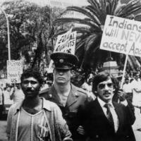A policeman arrests two Indian men of South Africa