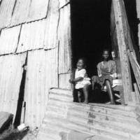A mother and her child photographed in a corrugated iron shack